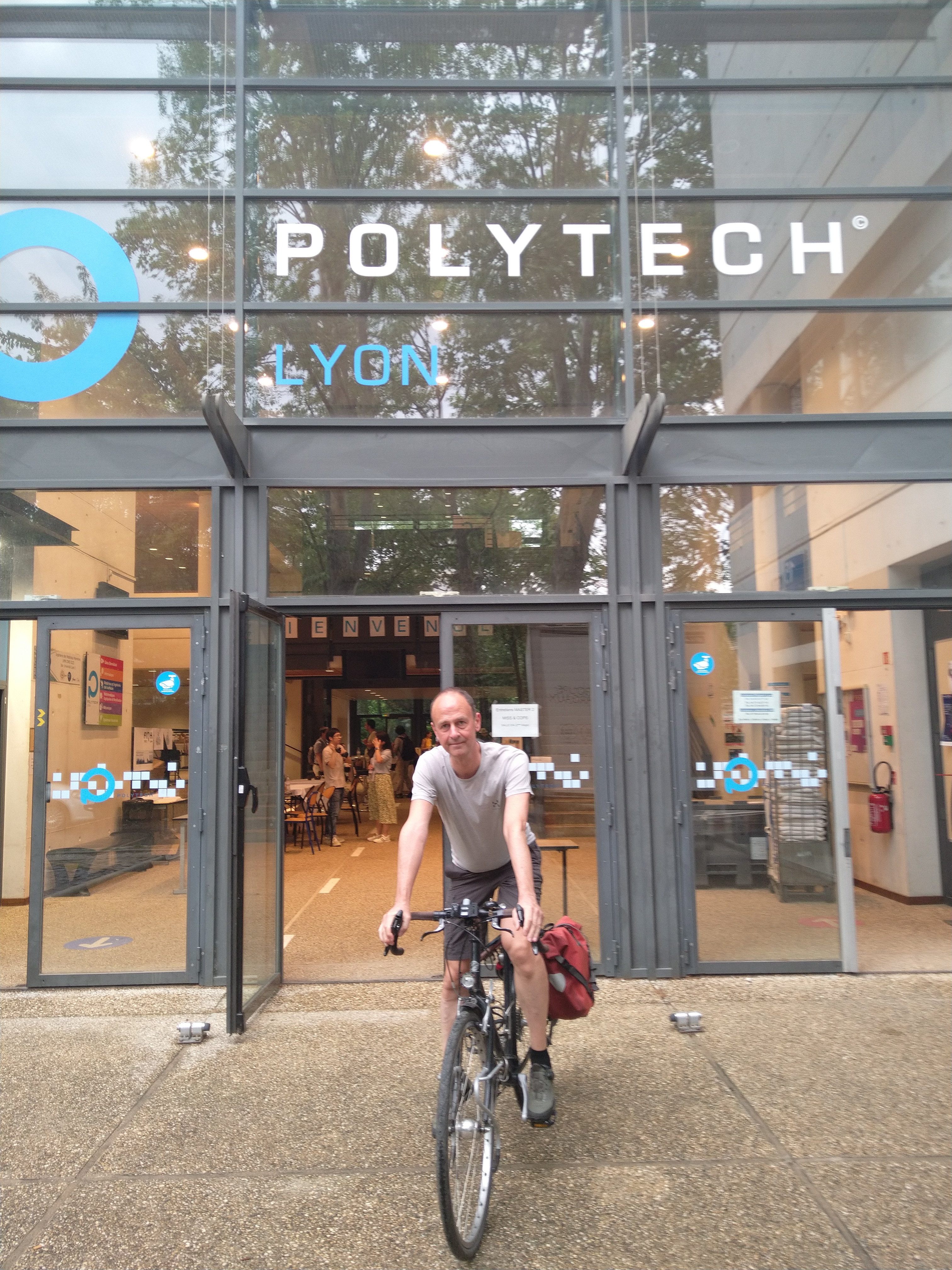 photo of Mark Potse on his traveling bicycle in front of the
	 Polytech Lyon meeting where the 2023 FIMH meeting was held.